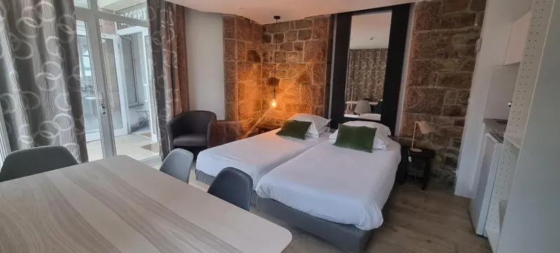 Une chambre lumineuse avec deux lits simples et un coin repas.