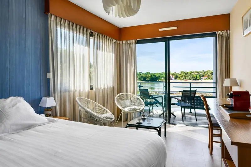 Une chambre lumineuse s'ouvre sur une terrasse avec vue sur l'eau.