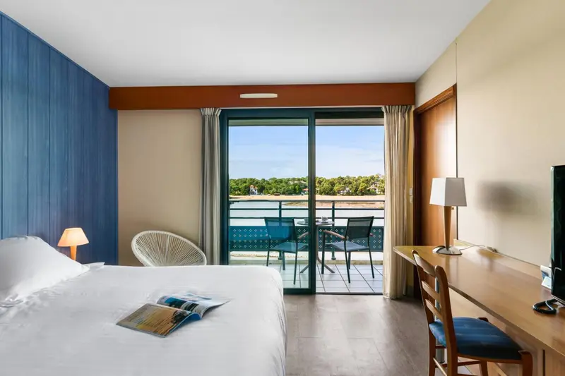 Chambre lumineuse avec un lit et un accès à une terrasse vue sur mer.
