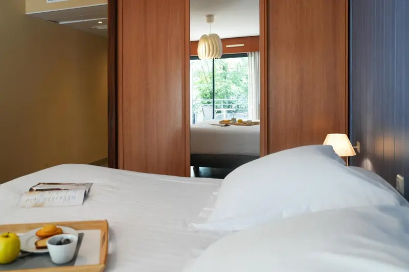 Un lit blanc est dressé dans une chambre lumineuse.