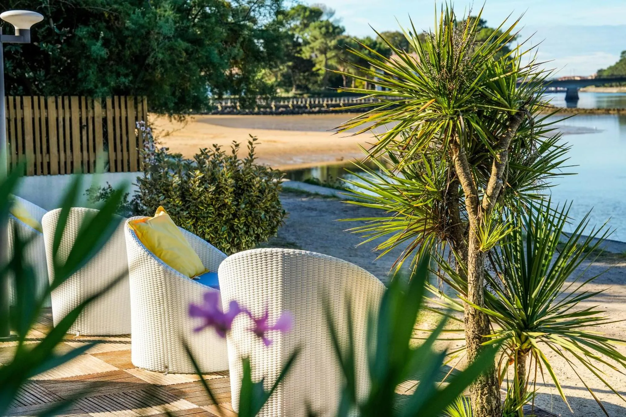 Mobilier d'extérieur blanc sur une terrasse en bois face à la mer.
