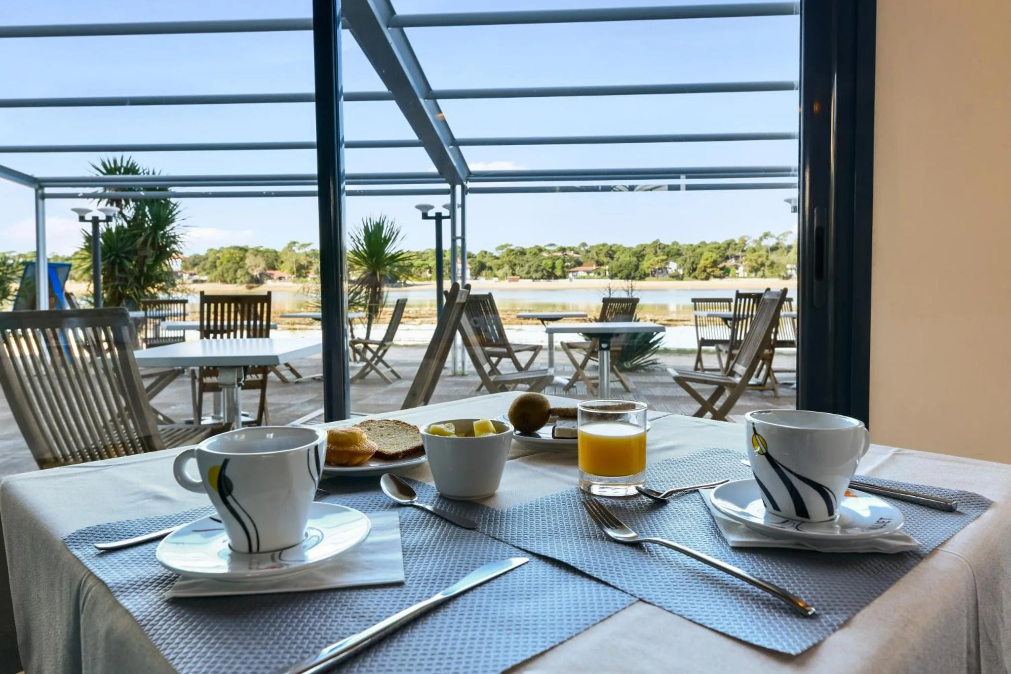 Une table est dressée avec un petit déjeuner face à une vue sur la mer.