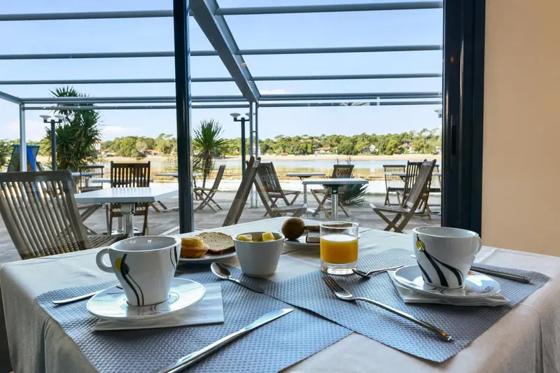 Une table est dressée avec un petit déjeuner face à une vue sur la mer.