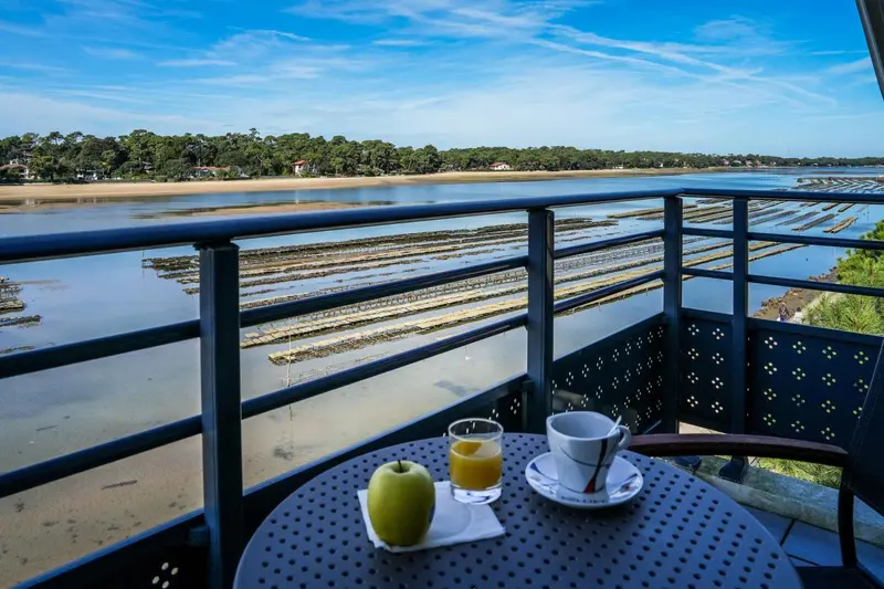 Une table avec un petit-déjeuner est posée sur un balcon avec vue sur l'estuaire et les parcs à huîtres.