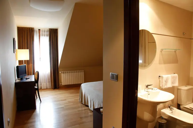 Une chambre lumineuse avec un bureau et un accès à une salle de bain.