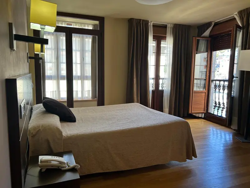 Une chambre lumineuse avec un grand lit et un balcon.