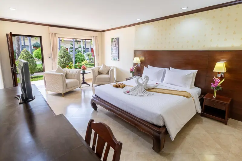 Chambre lumineuse avec un grand lit et un coin salon.