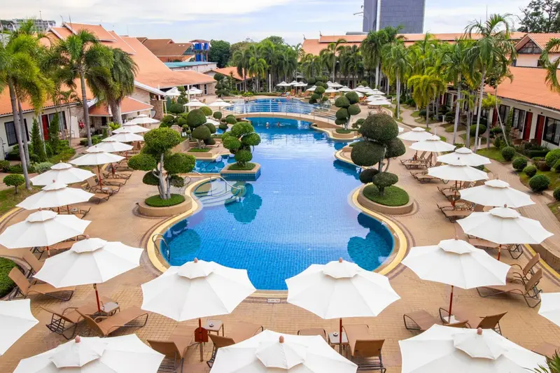 Vue aérienne d'une piscine entourée de transats et de végétation tropicale.