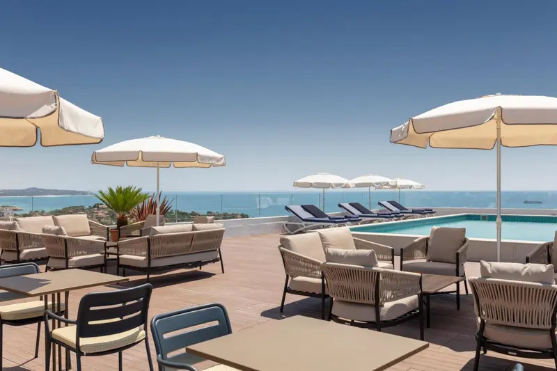 Terrasse aménagée avec des transats et des tables offrant une vue sur la mer.