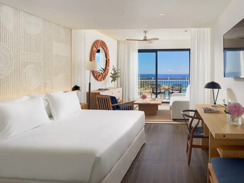 Chambre lumineuse avec un grand lit et une vue sur la mer.