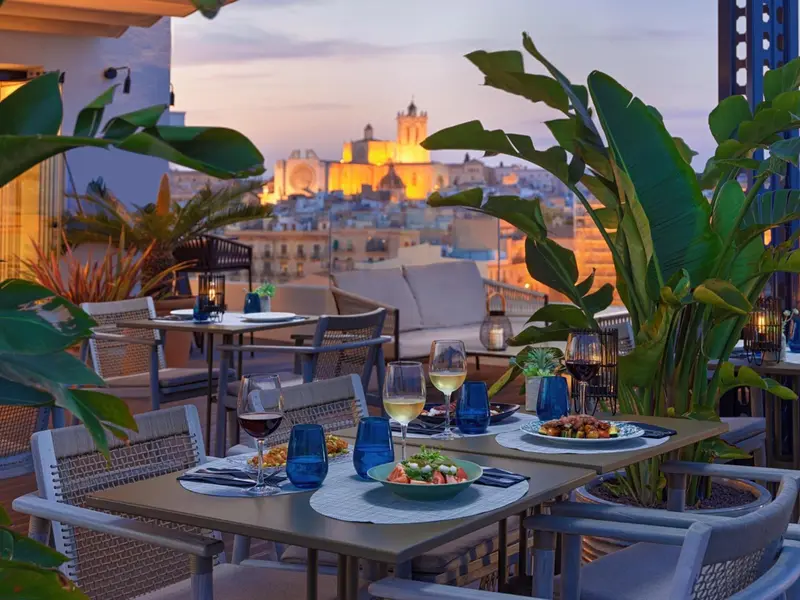 Tables dressées avec des plats et des boissons sur une terrasse en soirée.