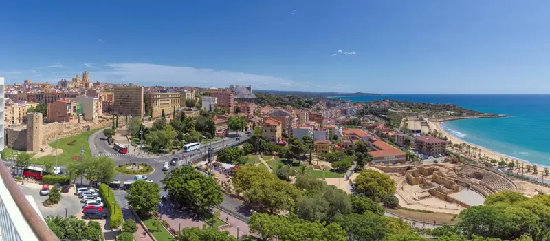 Vue aérienne d'une ville côtière avec des bâtiments, des espaces verts et une plage.
