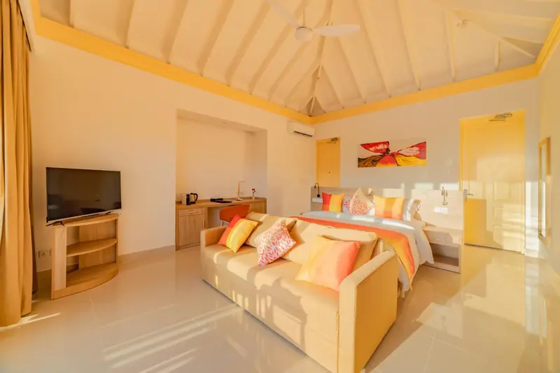 Une chambre lumineuse avec un canapé et un lit décoré de coussins.