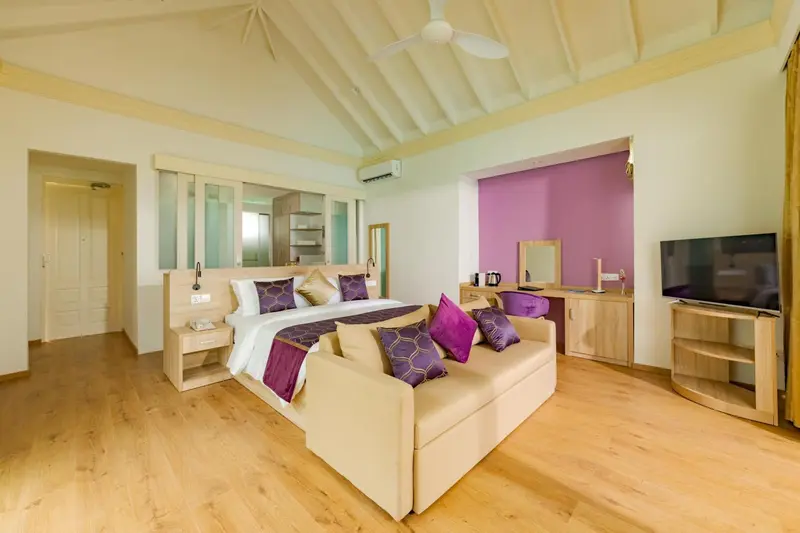 Une chambre lumineuse avec un lit double et un coin salon.