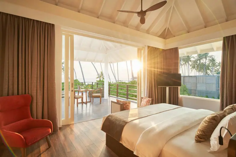 Une chambre lumineuse s'ouvre sur une terrasse avec vue sur la végétation.