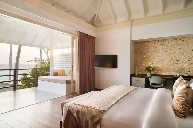 Une chambre lumineuse avec un lit et un espace détente donnant sur l'océan.