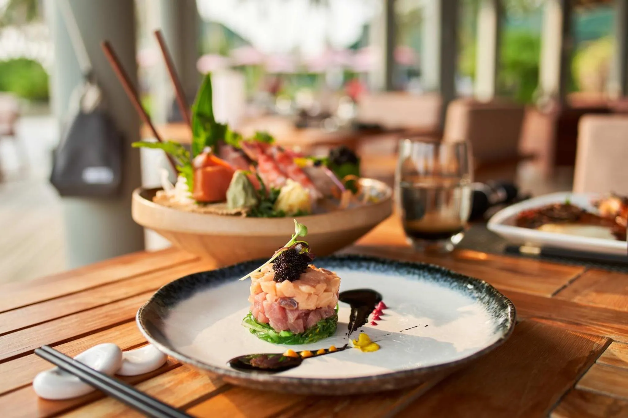 Assiette de poisson cru décorée, présentée sur une table en bois.