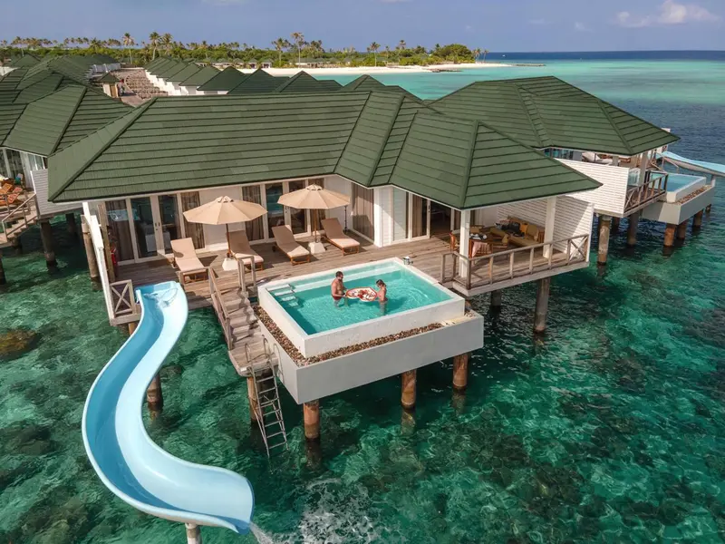Vues aériennes de villas sur pilotis avec piscines privées et toboggans.