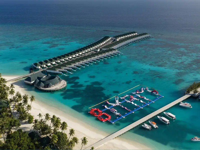 Vue aérienne d'un complexe hôtelier sur pilotis avec une plage et un centre de sports nautiques.