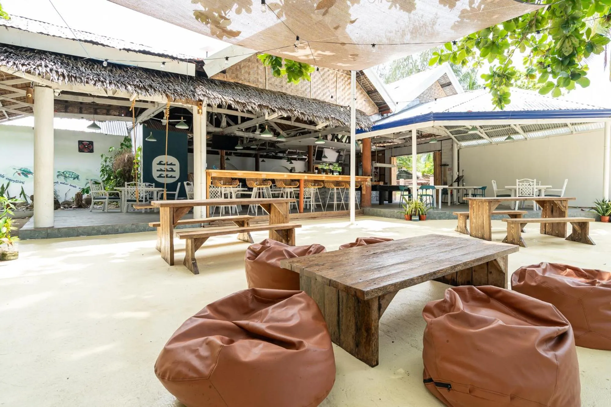 Espace de restauration extérieur avec tables et chaises sous une tonnelle.