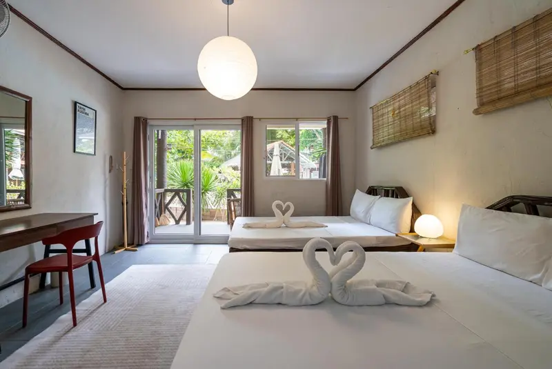 Une chambre lumineuse avec un lit double décoré de serviettes en forme de cygnes.