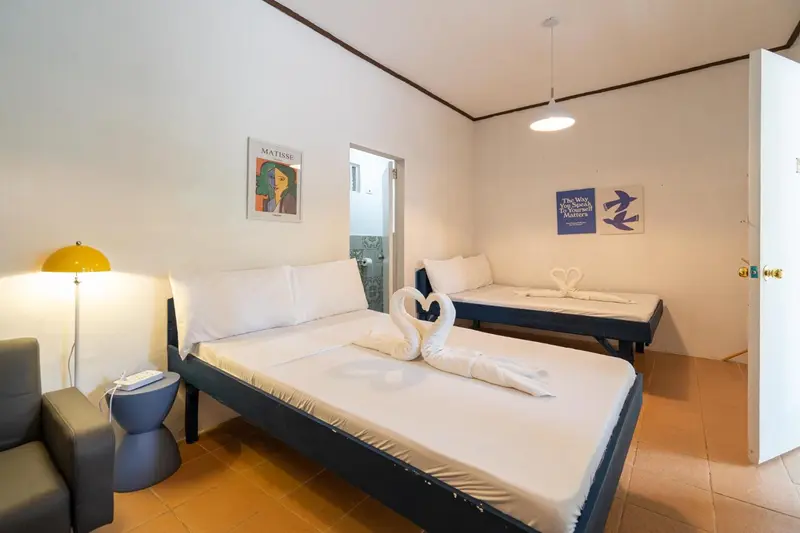 Une chambre lumineuse avec deux lits simples décorés de serviettes en forme de cygnes.