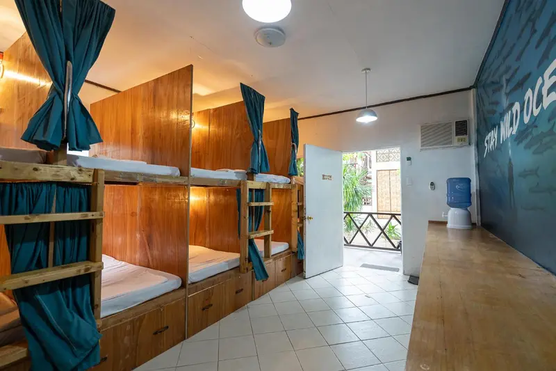 Intérieur clair d'une chambre avec plusieurs lits superposés en bois.