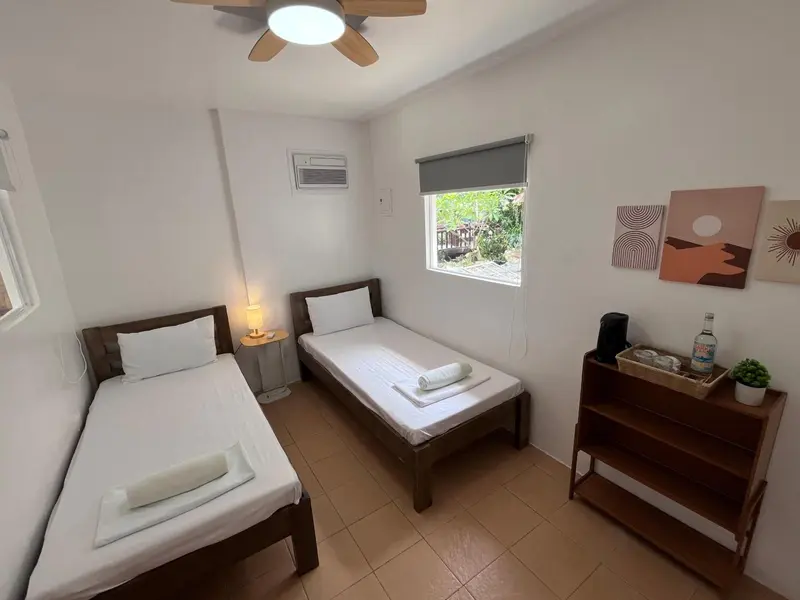 Une chambre lumineuse avec deux lits simples et une décoration murale.