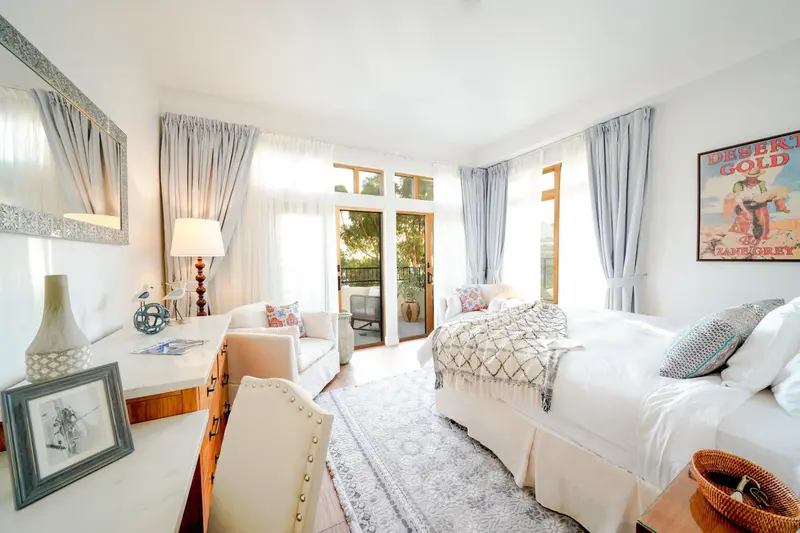 Chambre lumineuse avec un lit recouvert d'une courtepointe et un coin salon.