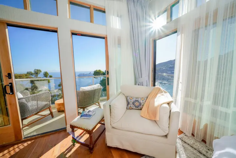 Un fauteuil confortable est placé près de larges baies vitrées donnant sur une vue sur la mer.