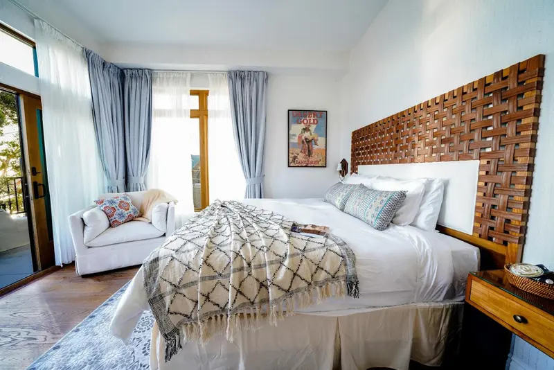 Une chambre lumineuse avec un grand lit et un fauteuil.