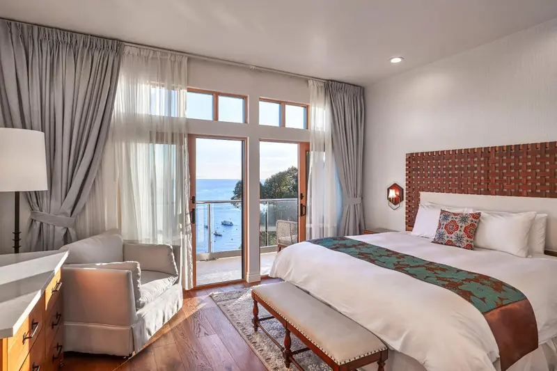 Une chambre lumineuse avec un grand lit et un coin salon donnant sur une vue mer.