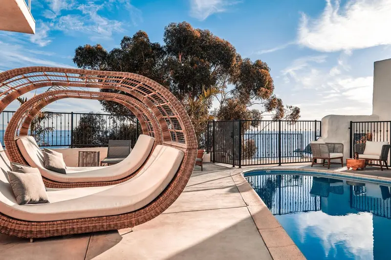 Espace de détente extérieur avec mobilier en osier et piscine turquoise.