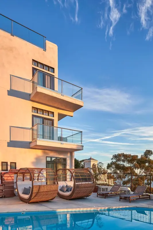 Façade d'un bâtiment moderne avec des transats au bord d'une piscine.
