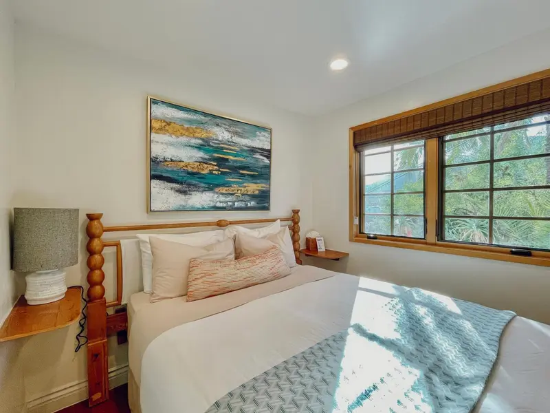 Une chambre lumineuse avec un grand lit et une décoration murale abstraite.