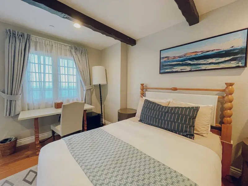 Une chambre lumineuse avec un lit et un bureau près d'une fenêtre.