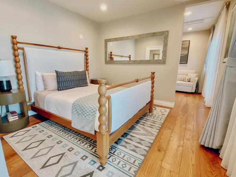 Une chambre lumineuse avec un grand lit à baldaquin et un tapis décoratif.