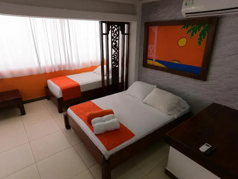 Chambre lumineuse avec deux lits simples et une décoration murale colorée.