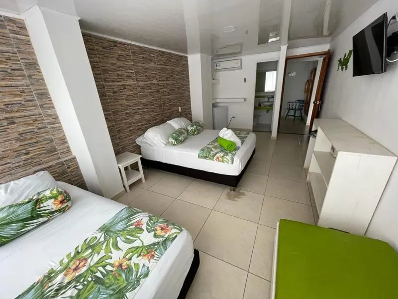 Chambre lumineuse avec lits décorés de motifs tropicaux et coin repas.