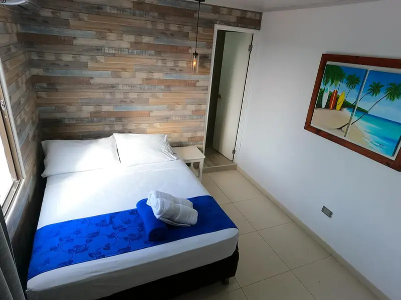 Une chambre lumineuse avec un grand lit recouvert d'une courtepointe bleue et de serviettes.