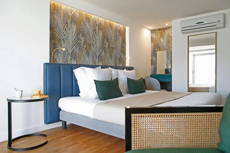 Une chambre lumineuse avec un grand lit recouvert de coussins verts.