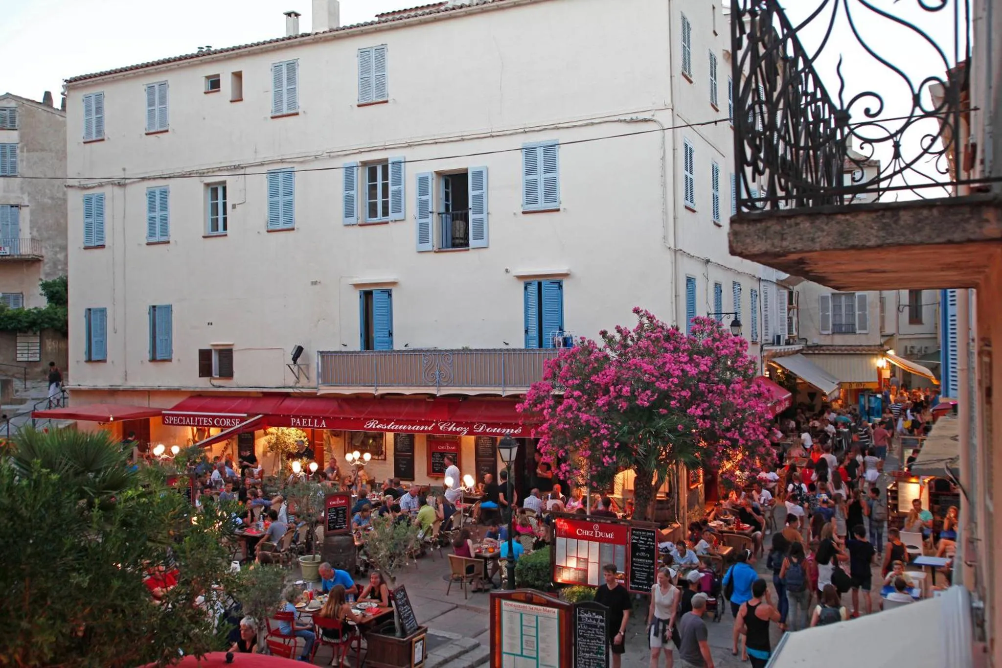 Terrasse animée d'un restaurant en bord de rue avec des tables et des clients.