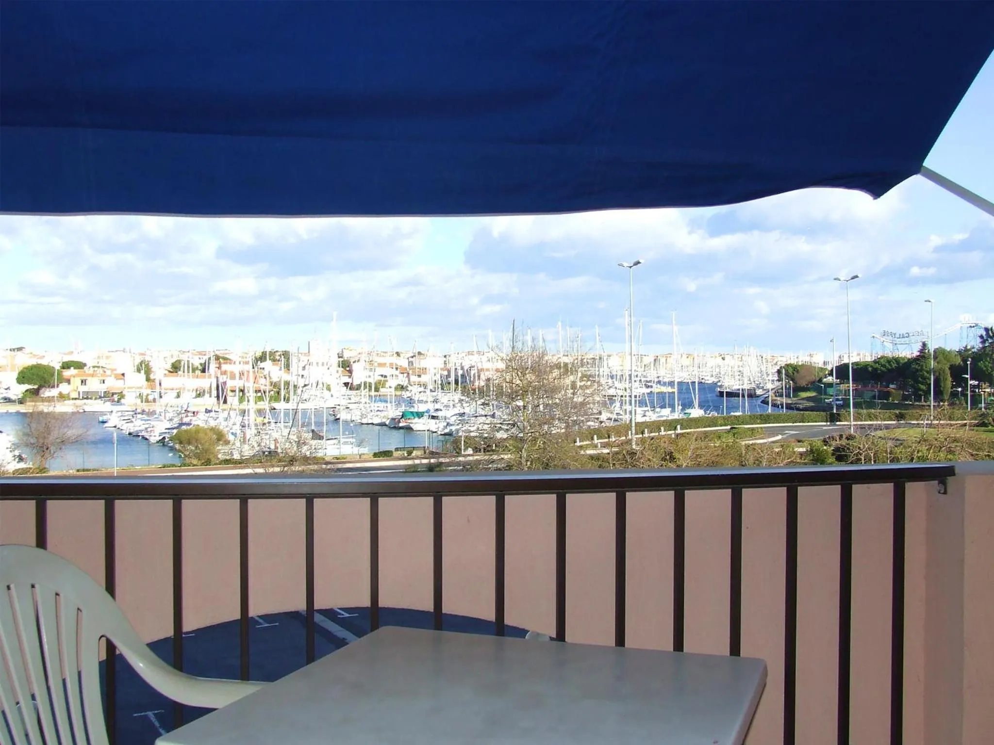 Vue sur un port de plaisance depuis une terrasse ombragée.