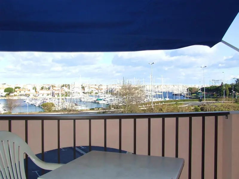 Vue sur un port de plaisance depuis une terrasse ombragée.