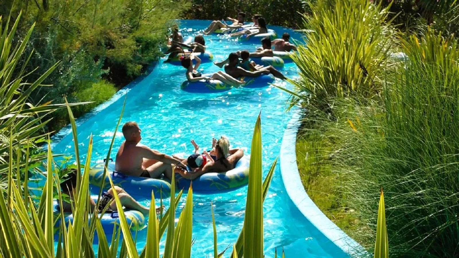 Des personnes se détendent sur des bouées dans une rivière artificielle sinueuse.