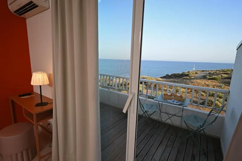 Une chambre lumineuse s'ouvre sur une terrasse avec vue sur la mer.