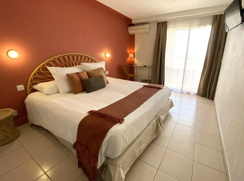 Une chambre lumineuse avec un grand lit recouvert d'une courtepointe et de coussins.