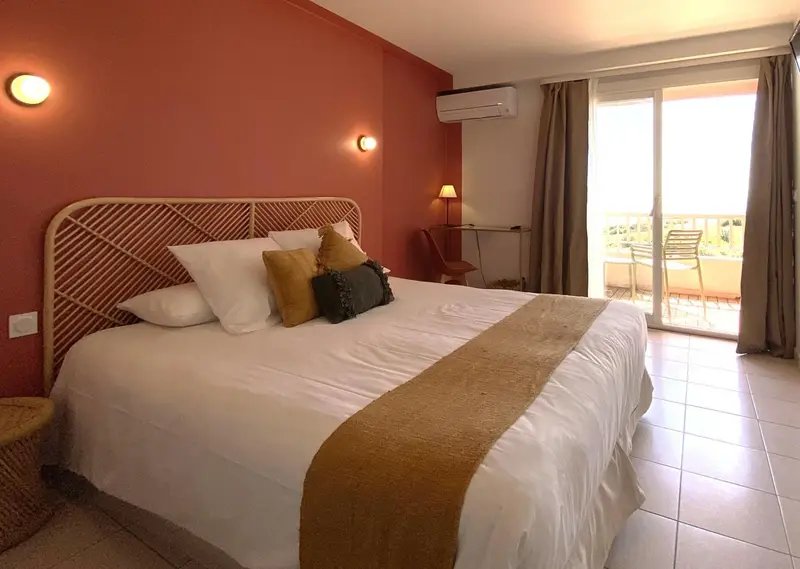 Une chambre lumineuse avec un grand lit et un accès à une terrasse.