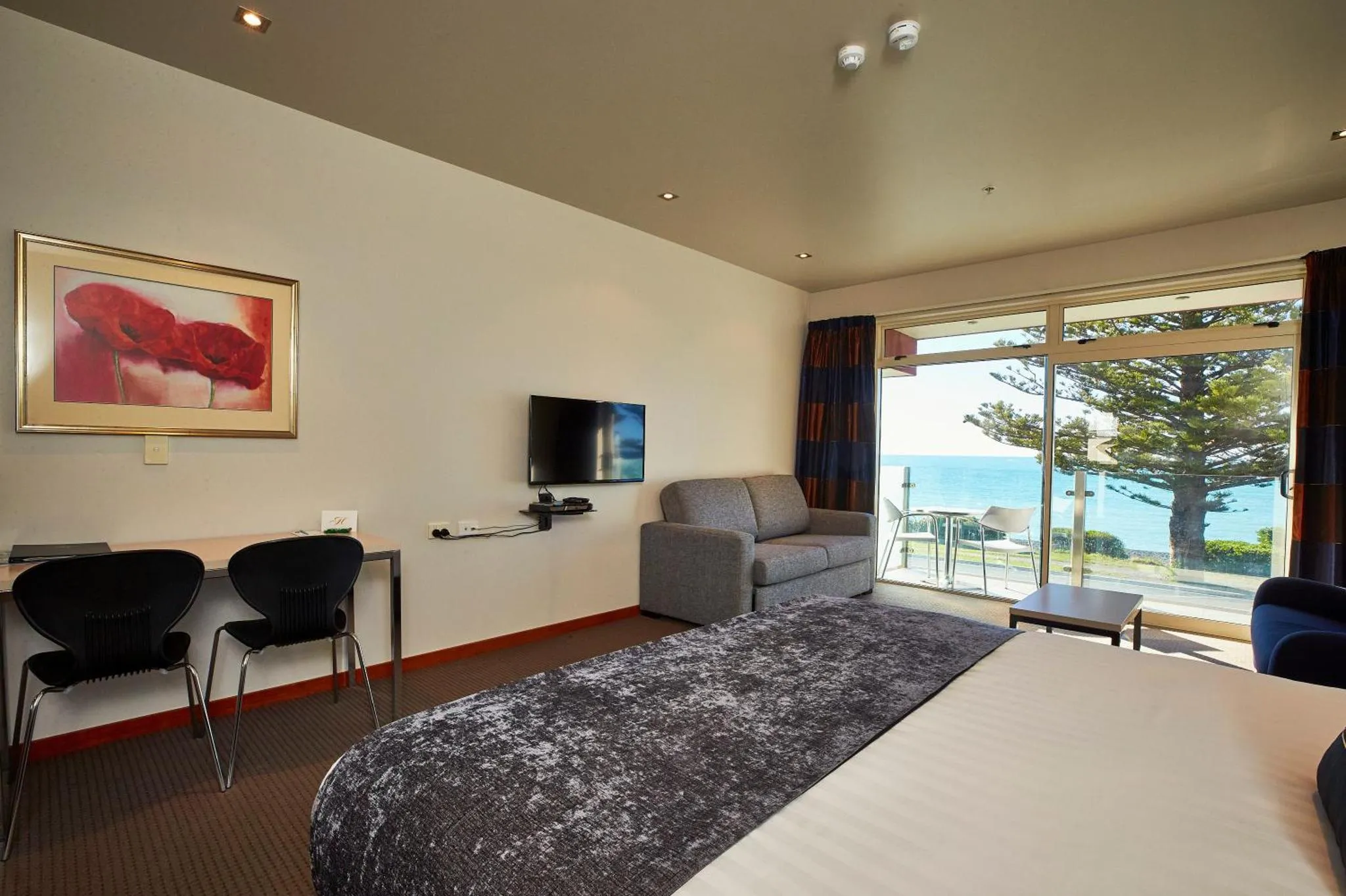 Espace de vie intérieur avec canapé, bureau et vue sur la mer.