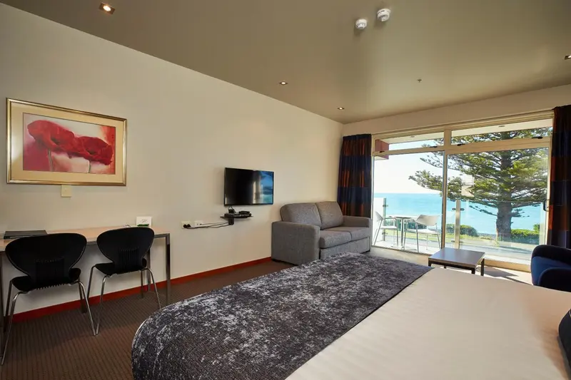 Espace de vie intérieur avec canapé, bureau et vue sur la mer.